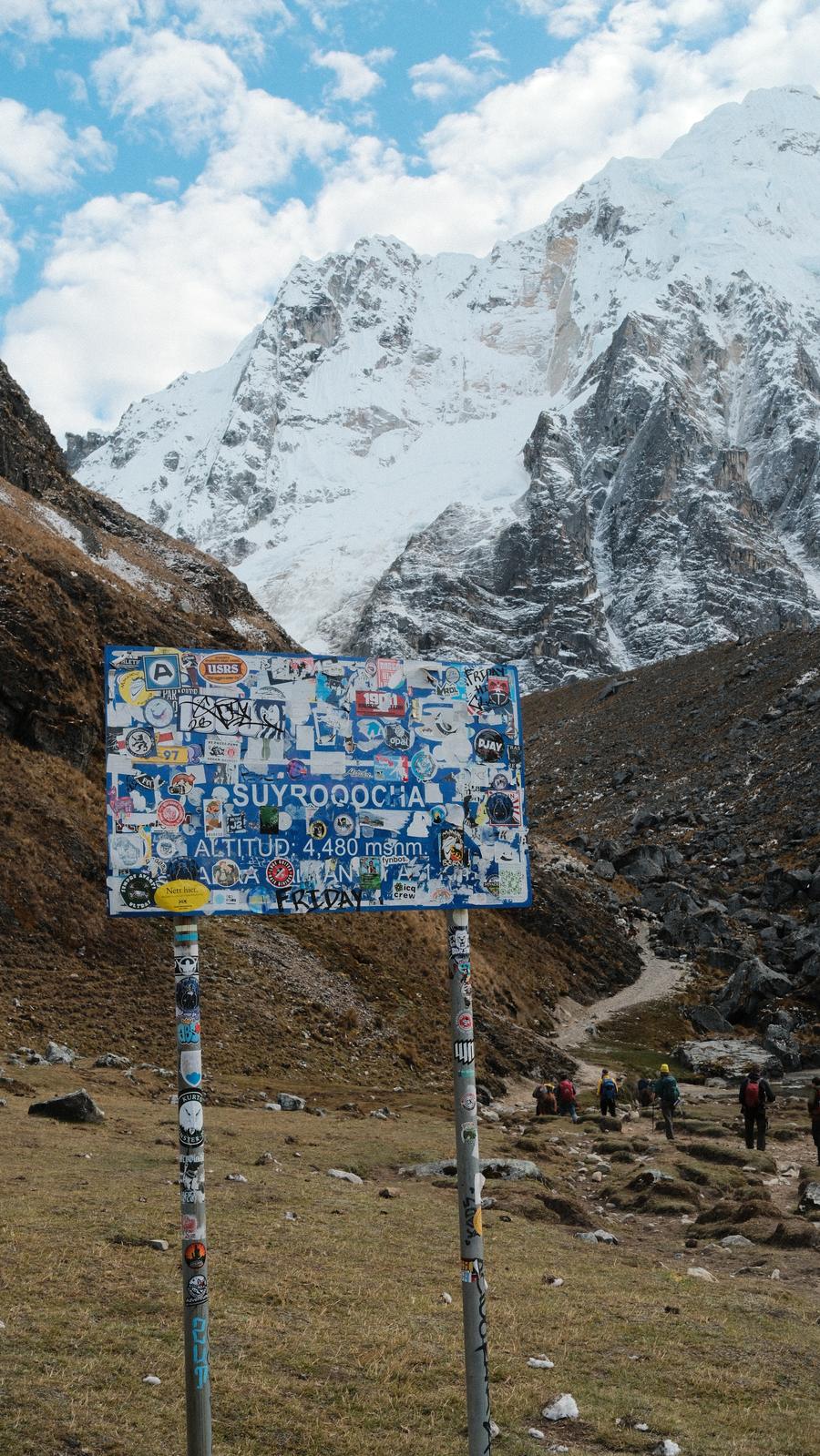 Salkantay Pass summit sign at 4,480 metres altitude, snow peaks behind